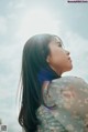 A woman with long black hair looking up at the sky.