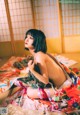 A woman in a kimono sitting on a bed.