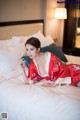 A woman in a red kimono laying on a bed.