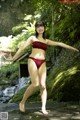 A woman in a red bikini standing on a rock.