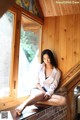 A woman sitting on a window sill in front of a window.