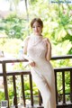 A woman in a white dress posing on a balcony.