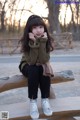 A little girl sitting on a wooden bench in a park.