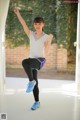 A young girl in a white shirt and black leggings doing a yoga pose.