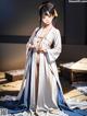 A woman in a white and blue kimono standing on a wooden floor.