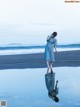 A woman in a blue dress standing on a beach.