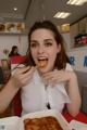 A woman sitting at a table eating a piece of pizza.