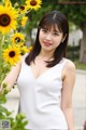 A woman standing in front of a bunch of sunflowers.