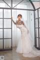 A woman in a wedding dress standing in front of a window.