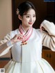 A woman in a white and gold hanbok is posing for a picture.