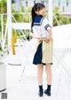 A young girl in a school uniform standing on a balcony.