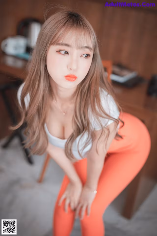 A woman in a white shirt and orange pants posing for a picture.